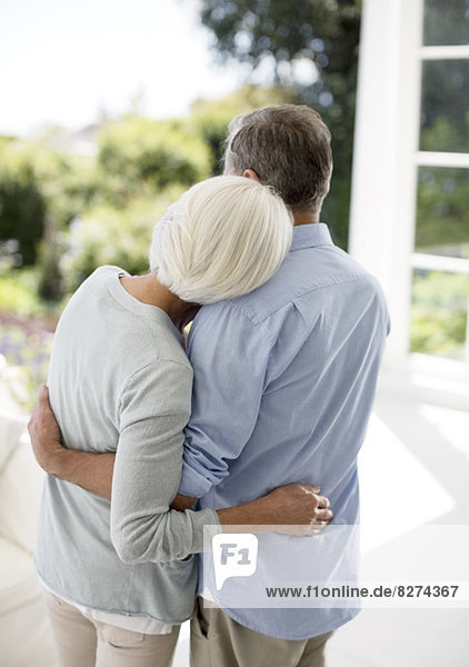 Seniorenpaar umarmt sich auf der Terrasse