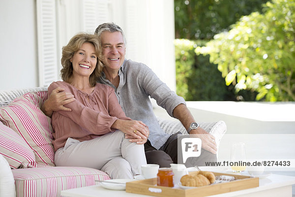 Porträt eines lächelnden Seniorenpaares beim Frühstück auf der Terrasse
