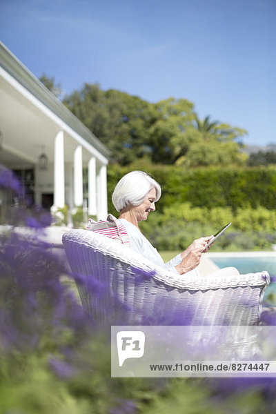 Seniorin mit digitalem Tablett im Garten