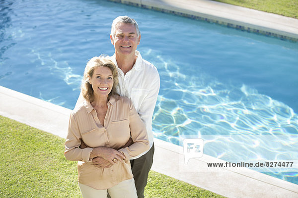 Porträt eines lächelnden Seniorenpaares am Pool