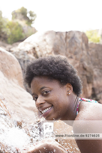 Porträt der lächelnden Frau am Wasserfall
