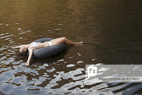 Frau schwimmt im Innenrohr im Fluss