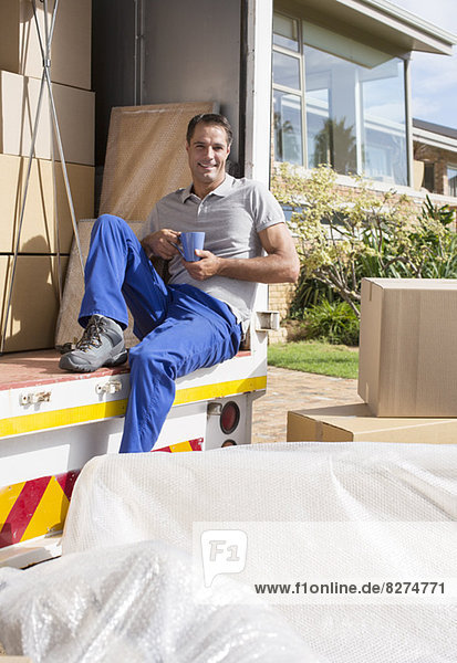 Mover enjoying cup of coffee in back of moving van