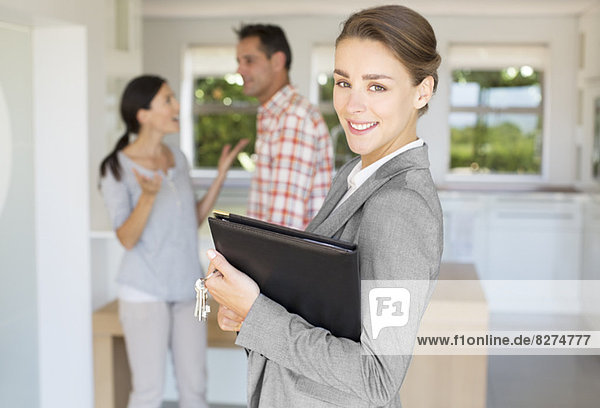 Portrait of smiling realtor with couple in background