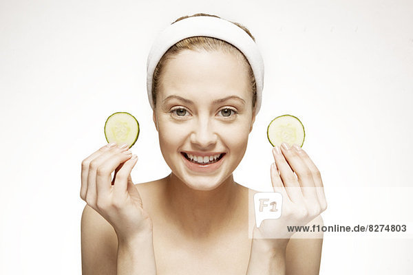 Smiling woman holding cucumber slices
