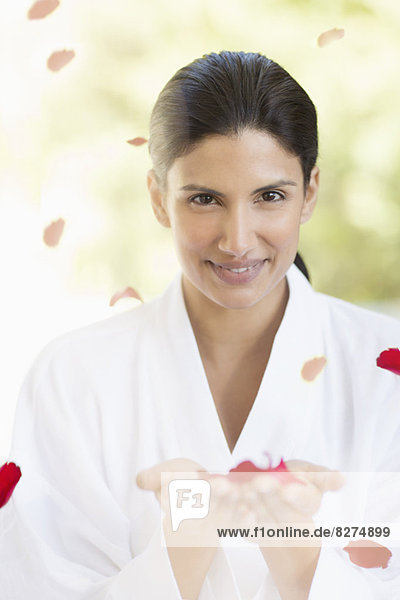 Portrait of smiling woman holding rose petals