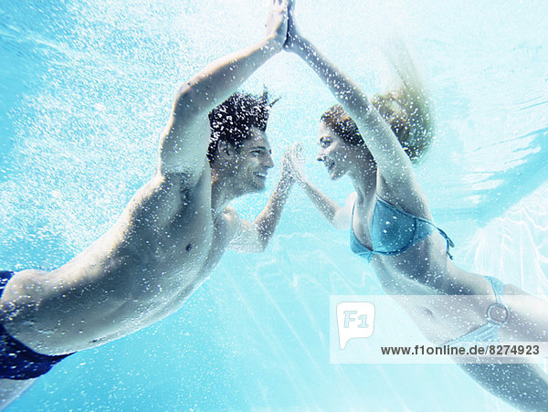 Couple touching hands underwater