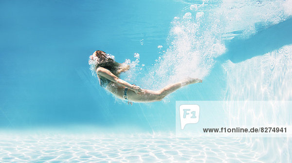 Frau schwimmt unter Wasser im Schwimmbad