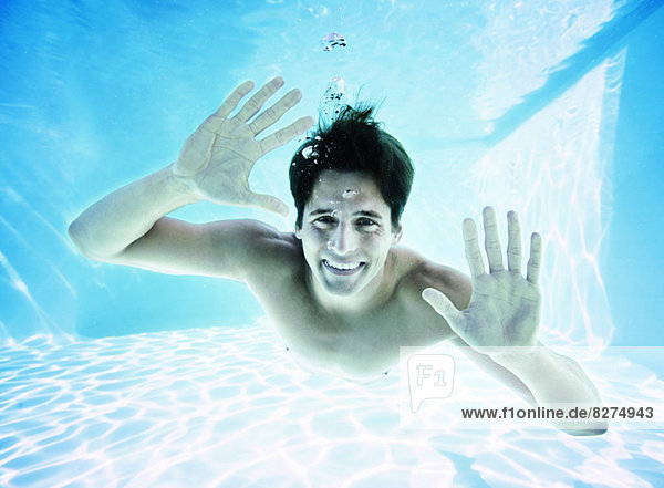 Porträt eines unter Wasser lächelnden Mannes im Schwimmbad