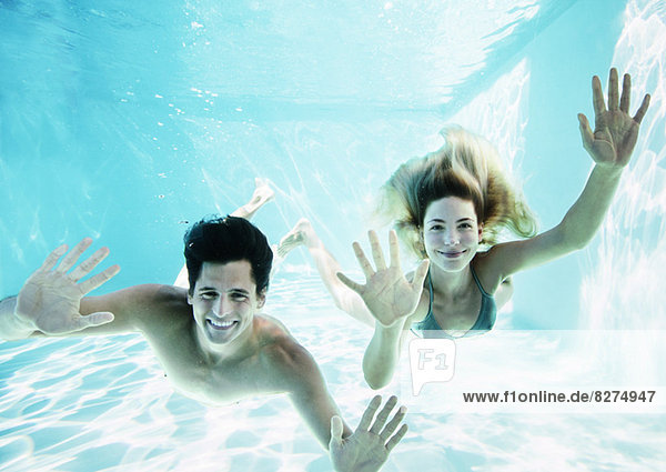 Portrait of smiling couple underwater in pool