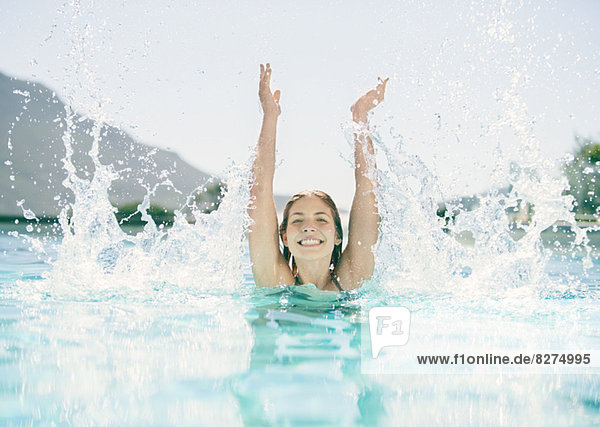 Woman splashing in swimming pool
