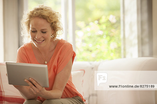 Frau mit digitalem Tablett auf dem Sofa