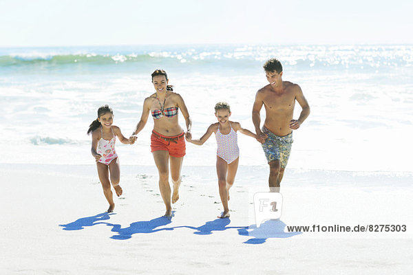 Familie beim Händchenhalten und Laufen am Strand