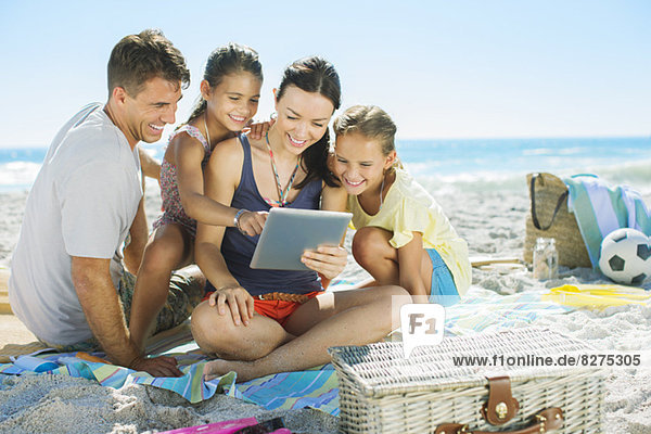 Family using digital tablet on beach