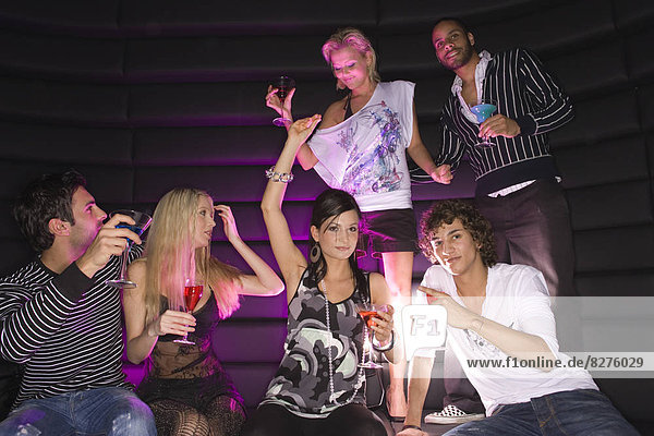 Young couple dancing in a nightclub with their friends having drinks