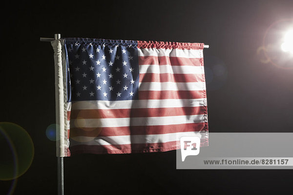 Eine amerikanische Flagge vor schwarzem Hintergrund  Spot beleuchtet