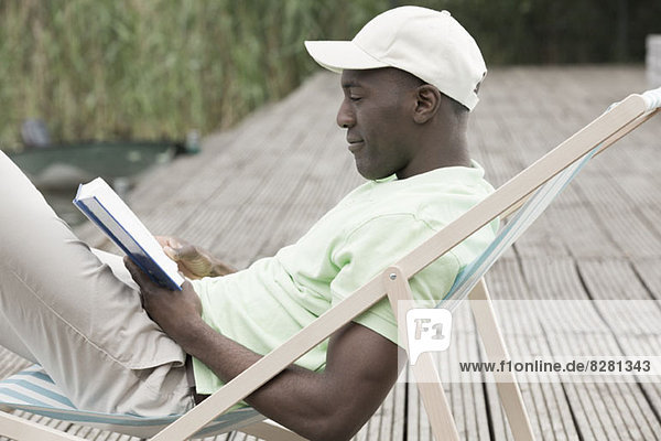 Man reading and relaxing on deck chair