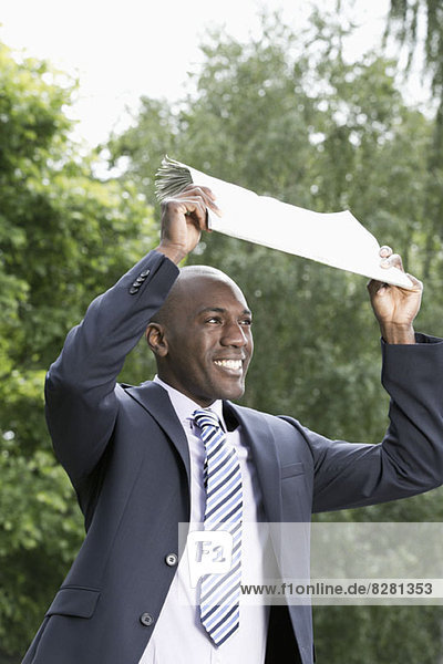 Happy businessman holding newspaper above head