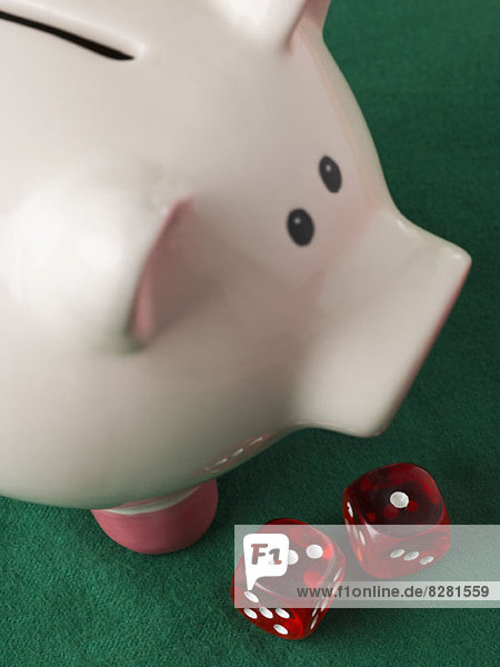 A piggy bank with two red die next to it