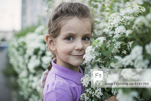 Ein junges Mädchen  das Blumen riecht.