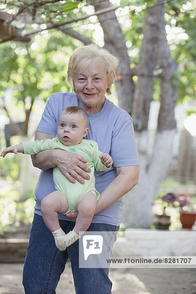 Eine fröhliche Großmutter hält ihren Enkel.