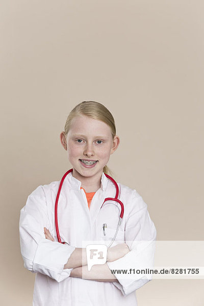 Ein lächelndes Mädchen in einem Laborkittel mit einem Stethoskop um den Hals.