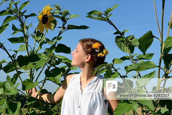 Lächelndes Mädchen greift nach einer Sonnenblume