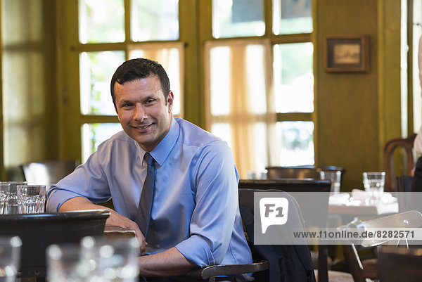 Geschäftsleute im Freien. Ein Latino-Mann  der allein an einem Tisch sitzt und sich entspannt.