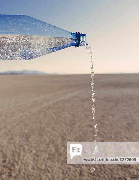 Die Landschaft der Schwarzen Felsenwüste in Nevada. Eine Flasche Wasser wird ausgegossen. Gefiltertes Mineralwasser.