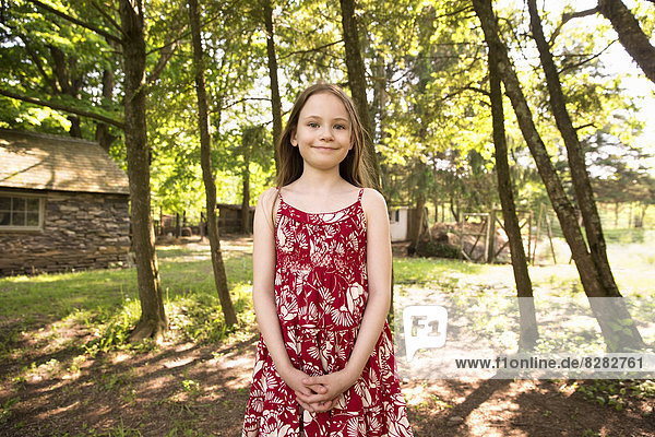 A Girl In A Summer Dress Standing In A Grove Of Trees.