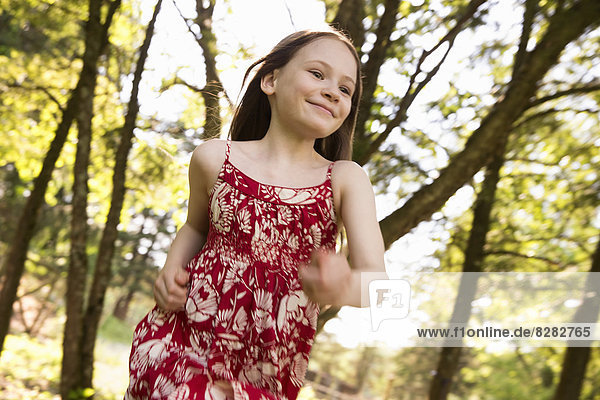 Ein junges Mädchen rennt auf einem Bauernhof durch die Bäume.