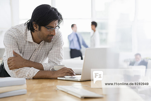 Büro. Ein junger Mann benutzt einen Laptop-Computer auf einem Schreibtisch.