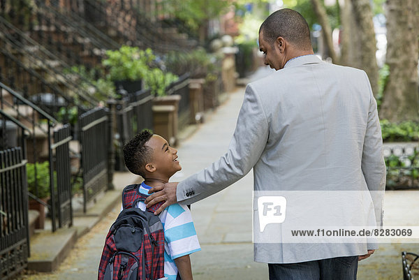 Ein Erwachsener und ein Kind  ein Vater und ein Sohn  die zusammen auf der Straße in der Stadt spazieren gehen.