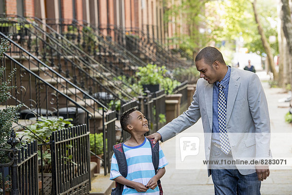 An Adult And A Child  A Father And Son  Walking Together On The Street In The City.
