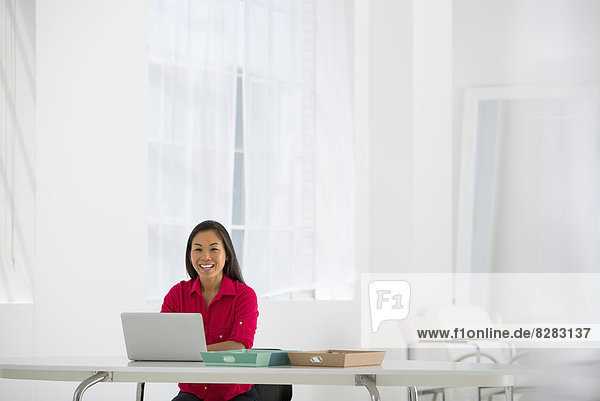 Asiatische Geschäftsfrau am Schreibtisch mit einem Laptop.