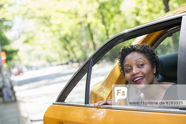 Eine Frau steigt aus dem hinteren Fahrgastsitz eines gelben Taxis aus.