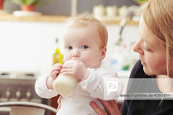 Mother and baby sitting in kitchen with baby bottle