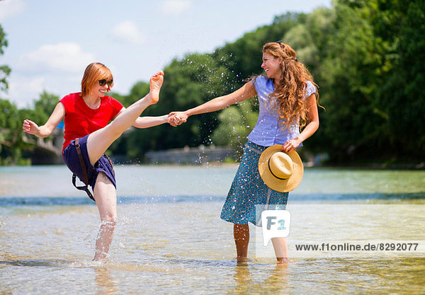 Two female friends playing in Isar River  Munich  Germany