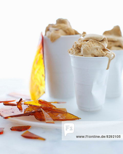 Stilleben mit Tassen aus gesalzenem Karamell-Eis und Toffeesplittern