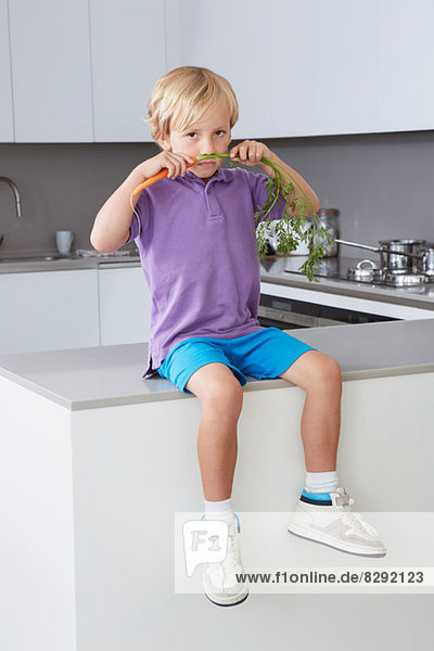 Junge sitzend in der Küche mit Karottenschnurrbart