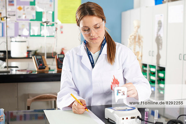Lab technician holding chemical sample and making notes