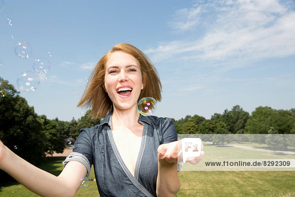 Junge Frau hat Spaß mit Blasen im Park
