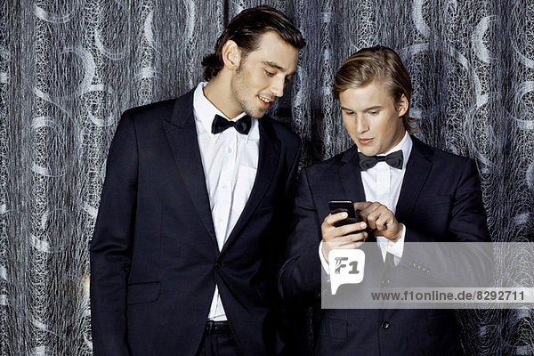 Porträt junger Männer beim Blick aufs Handy