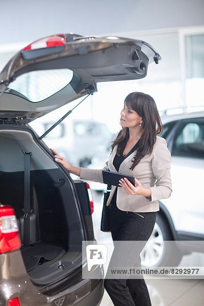 Mid adult woman checking car boot in showroom
