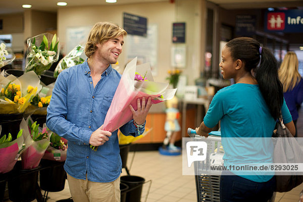 Junger Mann beim Einkaufen Blumenstrauß auswählen