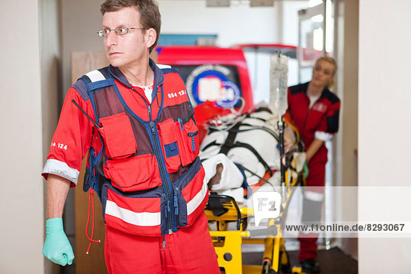 Rettungssanitäter fahren mit Krankentrage durchs Krankenhaus