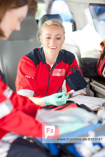 Two female paramedics in ambulance checking medical equipment