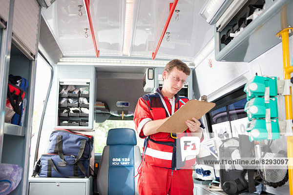 Paramedic in ambulance listing equipment