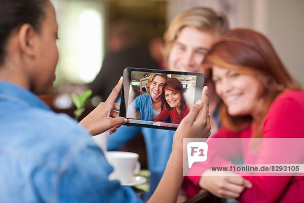 Gruppe von Freunden im Café beim Fotografieren mit digitalem Tablett