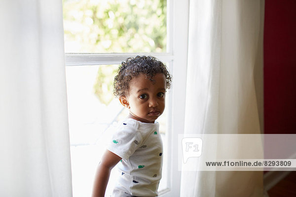 Kleinkind neben dem Fenster stehend